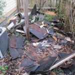 Chimney teardown debris on the ground-picket fence-vines and air condition to the left.