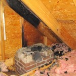 Fire chimney damage in attic rafter is charred black char laying around and on insulation
